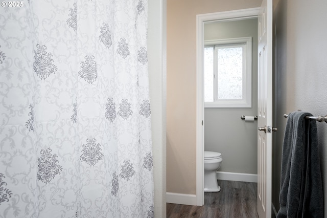 full bathroom featuring toilet, a shower with curtain, baseboards, and wood finished floors