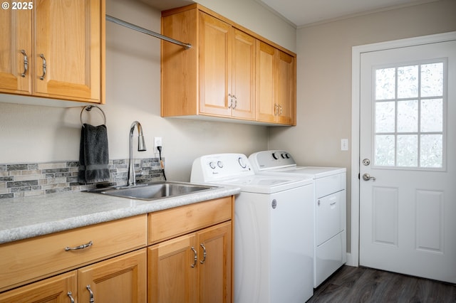 clothes washing area featuring washing machine and clothes dryer, dark wood-type flooring, sink, and cabinets