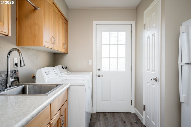 washroom with cabinets, crown molding, sink, washing machine and clothes dryer, and dark hardwood / wood-style floors