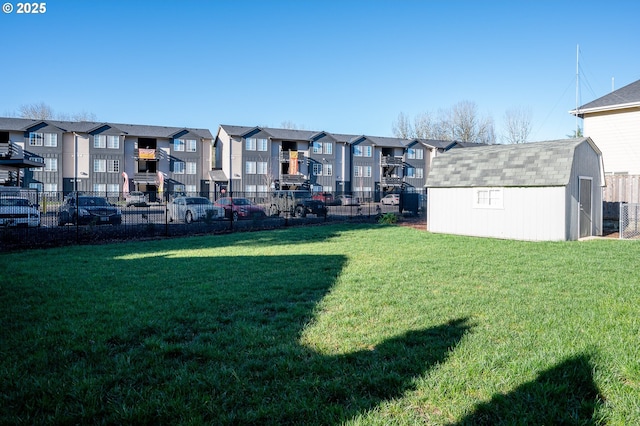 view of yard with an outdoor structure, a residential view, fence, and a storage shed