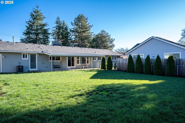 rear view of house featuring a yard, a chimney, and fence