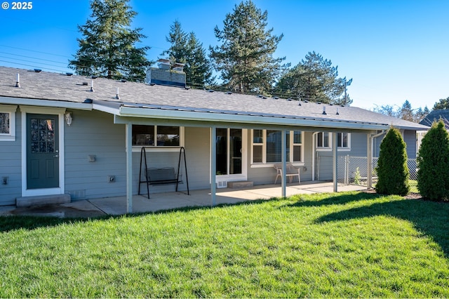 back of property featuring a yard, a patio, a chimney, and a shingled roof