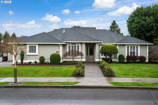 view of front of house with a shingled roof, stucco siding, and a front lawn