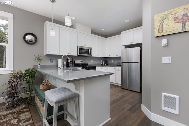 4145 SE Inlet Ave, Lincoln City, OR 97367 - kitchen featuring stainless steel appliances, a peninsula, dark wood-style floors, a sink, and a kitchen breakfast bar