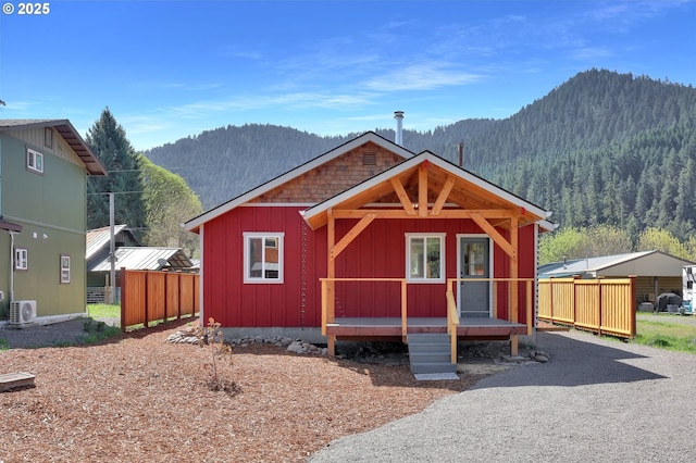 view of front of property featuring board and batten siding, ac unit, fence, and a mountain view