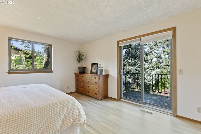 bedroom featuring light wood-style floors, access to outside, multiple windows, and visible vents