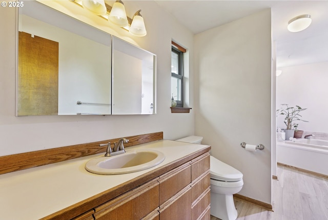 full bath with vanity, wood finished floors, toilet, baseboards, and a bathtub