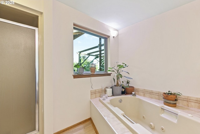 bathroom with a tub with jets, a shower stall, and baseboards