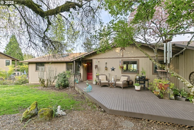 rear view of house featuring a lawn, a deck, and fence