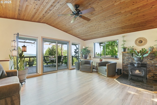 living area featuring wood ceiling, a ceiling fan, a wood stove, wood finished floors, and lofted ceiling