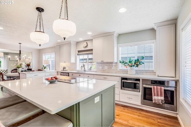603 Lone Oaks Loop, Silverton, OR 97381 - kitchen featuring stainless steel appliances, a peninsula, a textured ceiling, decorative backsplash, and a kitchen island