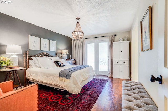 603 Lone Oaks Loop, Silverton, OR 97381 - bedroom featuring wood finished floors, access to exterior, a textured ceiling, and a chandelier