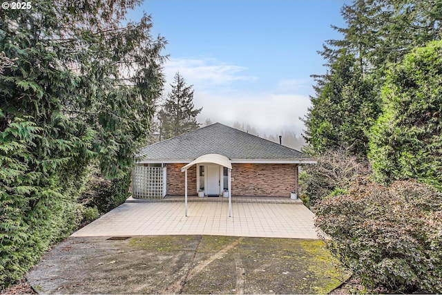 back of property featuring a patio area, stone siding, and a shingled roof