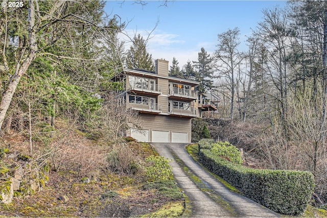 8408 NW Pinnacle Ct, Portland, OR 97229 - view of front of house with a balcony, a chimney, driveway, and a garage