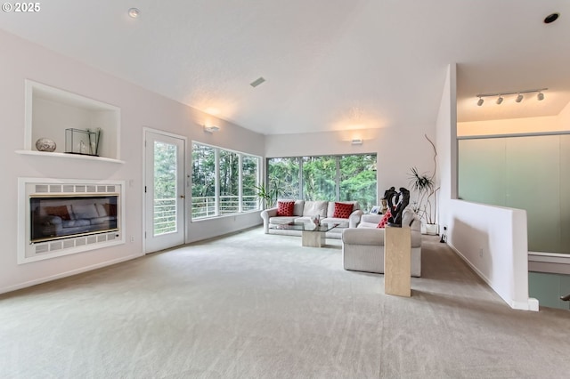 living room featuring track lighting, visible vents, carpet, lofted ceiling, and a glass covered fireplace