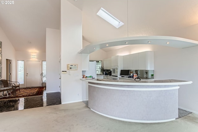 kitchen with white microwave, baseboards, high vaulted ceiling, a peninsula, and white cabinetry