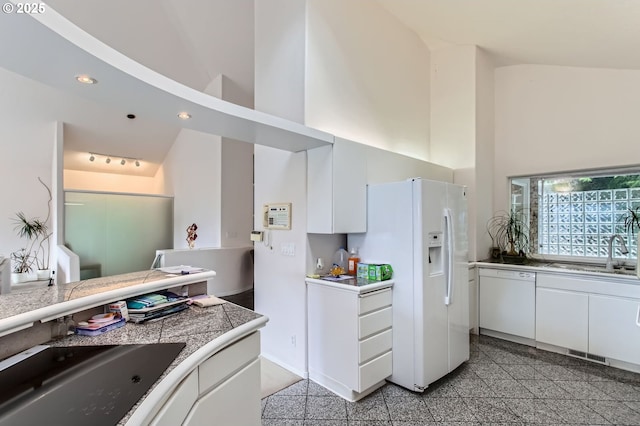 kitchen with white appliances, white cabinets, granite finish floor, and a sink