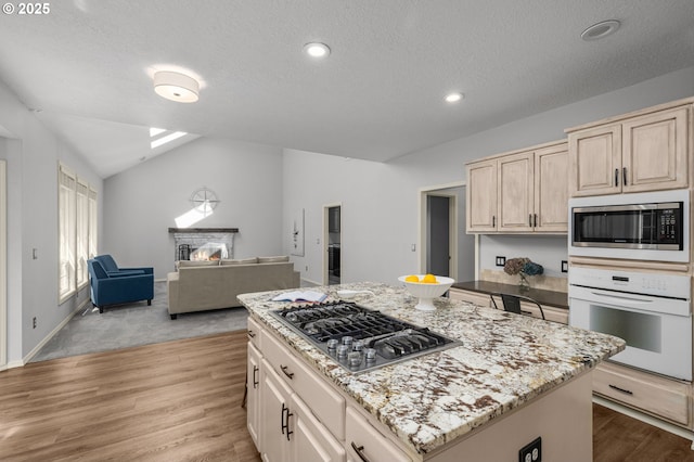 6783 Apollo Rd, West Linn, OR 97068 - kitchen featuring stainless steel appliances, light brown cabinets, open floor plan, vaulted ceiling, and light wood-type flooring