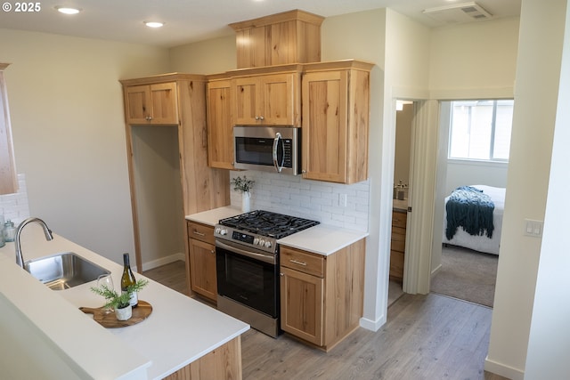 2368 Kingwood St, Forest Grove, OR 97116 - kitchen with appliances with stainless steel finishes, a sink, light wood-style flooring, tasteful backsplash, and light countertops