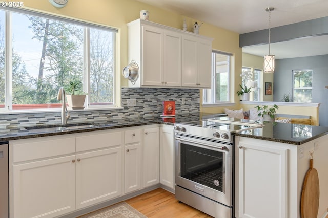 kitchen with sink, hanging light fixtures, a healthy amount of sunlight, stainless steel appliances, and white cabinets