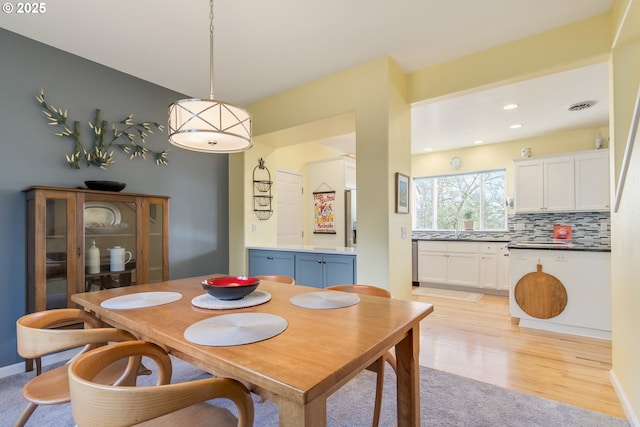 dining area with sink and light wood-type flooring