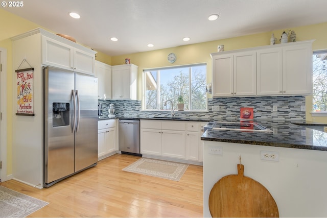 kitchen featuring backsplash, white cabinets, sink, dark stone countertops, and stainless steel appliances