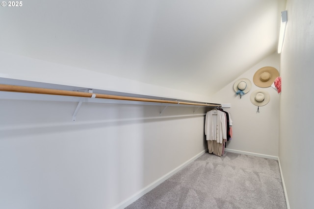 walk in closet with light colored carpet and lofted ceiling