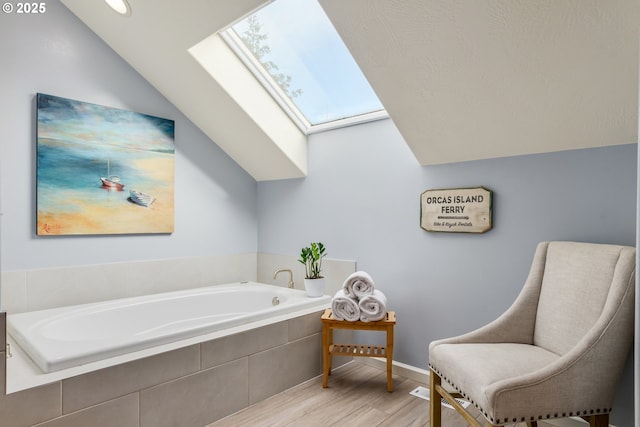 bathroom featuring a relaxing tiled tub, lofted ceiling with skylight, and hardwood / wood-style flooring