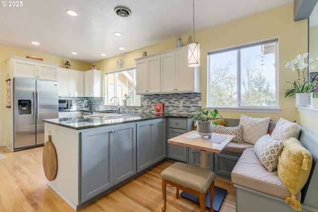 kitchen with gray cabinetry, stainless steel fridge with ice dispenser, pendant lighting, and a wealth of natural light