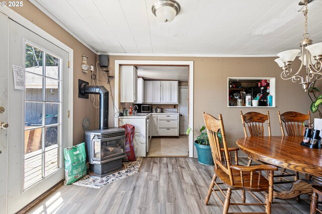 36285 Row River Rd, Cottage Grove, OR 97424 - dining space featuring separate washer and dryer, a wood stove, light wood-style flooring, and a chandelier