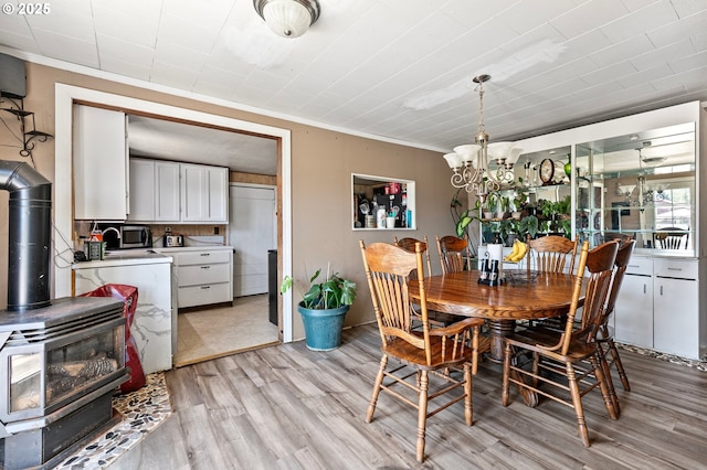 36285 Row River Rd, Cottage Grove, OR 97424 - dining space featuring a wood stove, light wood-style floors, a chandelier, ornamental molding, and washer / dryer