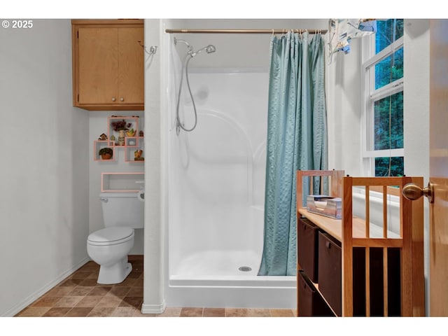 bathroom featuring toilet, baseboards, and a stall shower