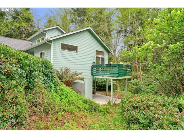 view of home's exterior featuring a wooden deck and a patio