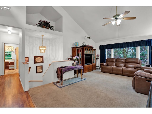 living room featuring high vaulted ceiling, ceiling fan with notable chandelier, and light wood finished floors