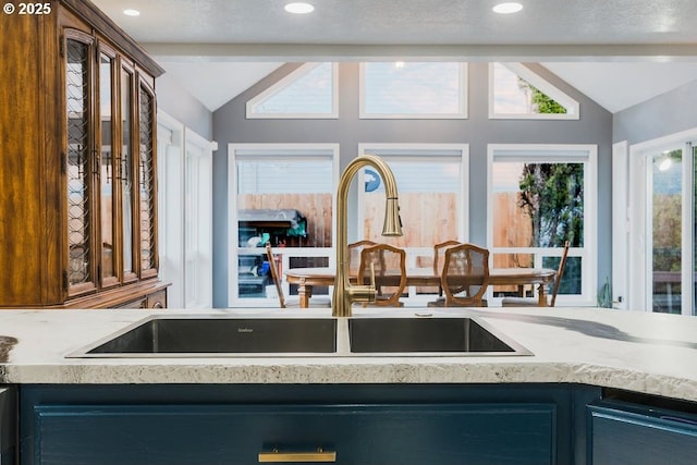 kitchen with recessed lighting, light countertops, vaulted ceiling, and a sink