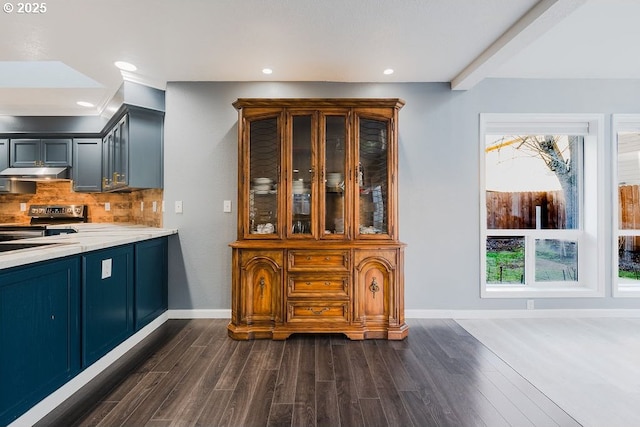 bar featuring baseboards, dark wood-type flooring, stainless steel electric range, under cabinet range hood, and backsplash