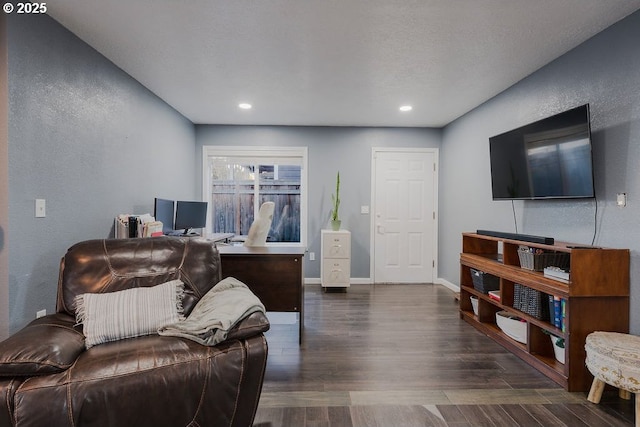 living room featuring a textured ceiling, baseboards, dark wood-style flooring, and a textured wall