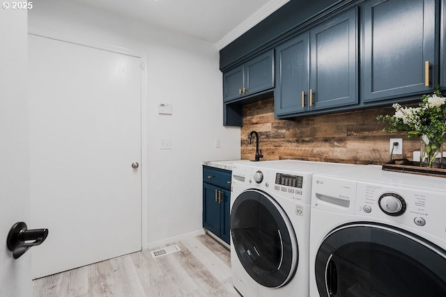 clothes washing area featuring cabinet space, baseboards, light wood-style flooring, independent washer and dryer, and a sink