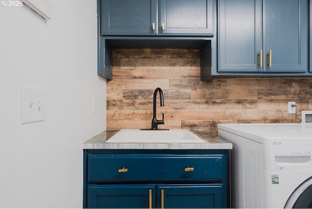 clothes washing area featuring washer / clothes dryer, cabinet space, a sink, and wood walls