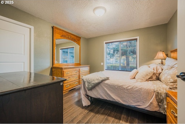 bedroom with a textured wall, dark wood finished floors, and a textured ceiling