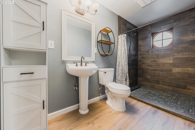 bathroom featuring visible vents, toilet, a stall shower, wood finished floors, and baseboards