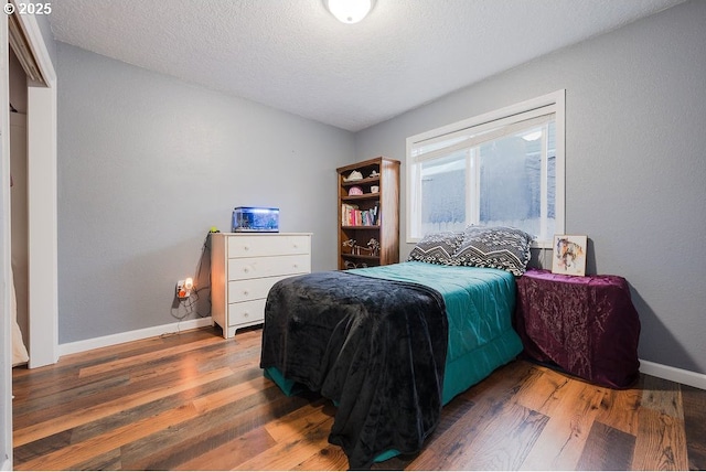 bedroom featuring dark wood-style floors, a textured ceiling, and baseboards