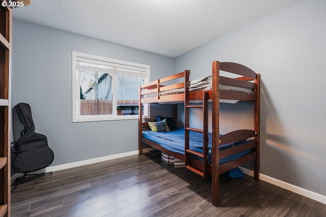 bedroom with a textured ceiling, baseboards, and dark wood-style flooring