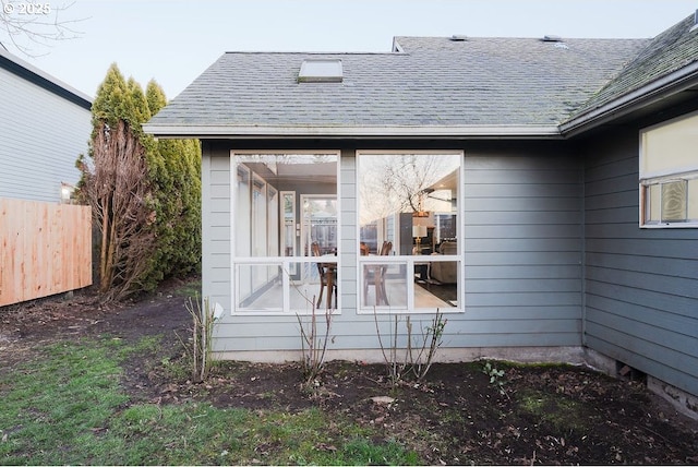 view of home's exterior featuring a shingled roof and fence