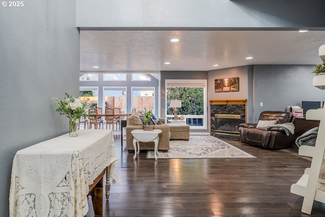 living room with recessed lighting, dark wood-style flooring, a textured wall, and a premium fireplace