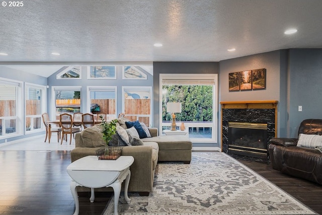 living room featuring a high end fireplace, vaulted ceiling, dark wood finished floors, and a textured ceiling