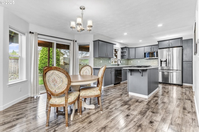 dining room featuring recessed lighting, baseboards, a notable chandelier, and wood finished floors