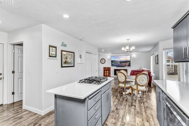 kitchen featuring stainless steel gas cooktop, light wood-style flooring, gray cabinetry, and light countertops