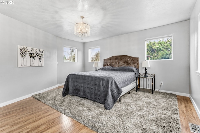 bedroom featuring multiple windows, wood finished floors, visible vents, and baseboards