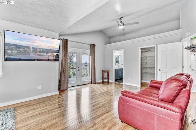 living room with french doors, baseboards, lofted ceiling, and wood finished floors